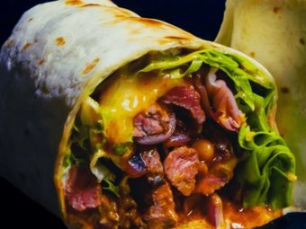 Herzhafter Wrap gefüllt mit gegrilltem Fleisch, Käse, Salat und Bohnen, appetitlich angeschnitten und serviert auf dunklem Hintergrund.