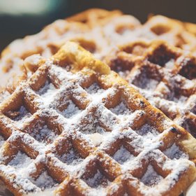 Frisch gebackene belgische Waffeln mit Puderzucker bestreut, goldbraun und knusprig, perfekt als süßes Streetfood-Dessert.