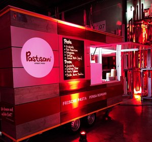 Roter Foodtruck „Pastsami Street Food“ bei Nacht, mit beleuchtetem Menü für frische Pasta und Pinsa Romana vor industrieller Kulisse.