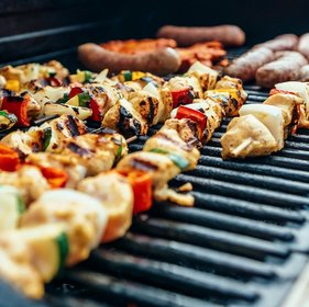 Bunte Fleischspieße mit Paprika, Zwiebeln und Zucchini sowie Bratwürste und Grillgut auf heißem Rost – Sommergrillen mit vielfältigem BBQ-Streetfood und rustikalem Geschmackserlebnis.