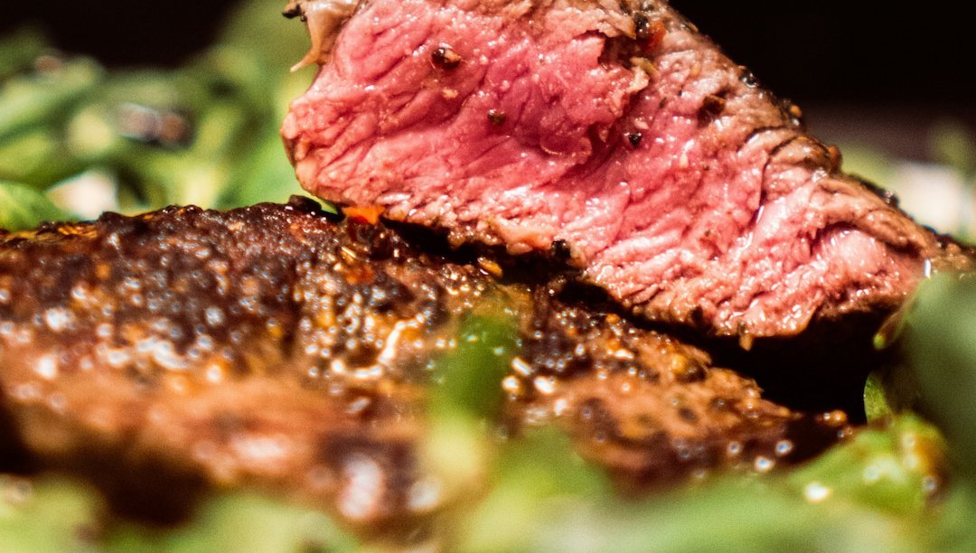 Saftiges Rindersteak medium gebraten, angeschnitten und serviert mit frischen grünen Beilagen in Nahaufnahme.