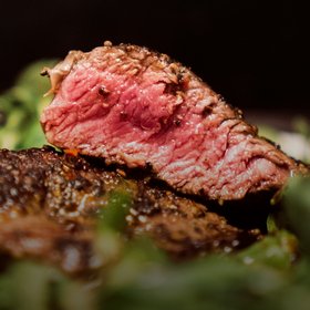 Saftiges Rindersteak medium gebraten mit rosa Kern auf einem Bett aus frischen Kräutern – hochwertiges Grillgericht für Fleischliebhaber.