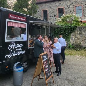 Foodtruck „Hessen meets Schwaben“ bei Event vor historischem Gebäude, Gäste im Gespräch mit Getränken und Speisen – stilvolles Streetfood-Catering im Freien.