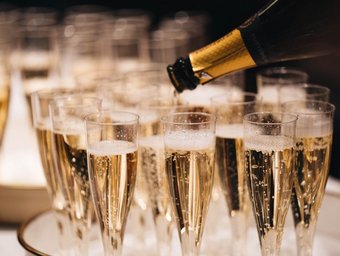 Sekt wird in mehrere Champagnergläser auf einem Tablett eingeschenkt, bereit für einen festlichen Anlass oder eine Feier.