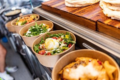 Frische italienische Streetfood-Gerichte in Pappschalen mit Pasta, Salat, Burrata und Pinsa, serviert in einem modernen Foodtruck.