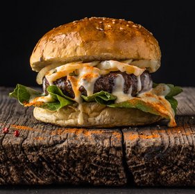 Saftiger Cheeseburger mit gegrilltem Patty, geschmolzenem Käse, Spiegelei und frischem Salat im Brioche-Bun – serviert rustikal auf Holz, ideal für Streetfood oder Burger-Liebhaber.
