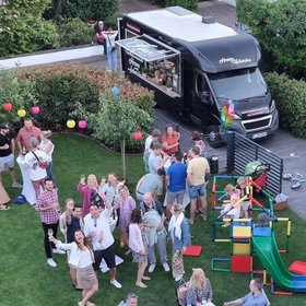 Fröhliches Gartenfest mit Foodtruck, spielenden Kindern und feiernden Erwachsenen auf grünem Rasen – bunte Dekoration und lockere Sommeratmosphäre bei privater Veranstaltung.